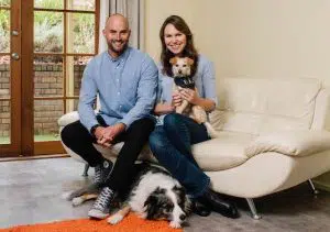 Morgan and Lara sitting on a couch with their two pooches
